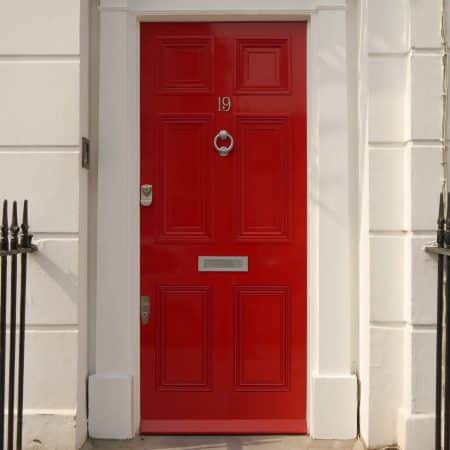 Red panel door with silver knocker and mailbox slot.