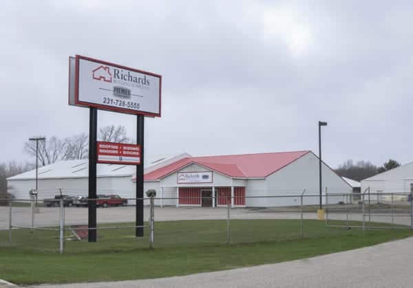Richards Building Supply in Muskegon, MI. Single story white building with red roof. .