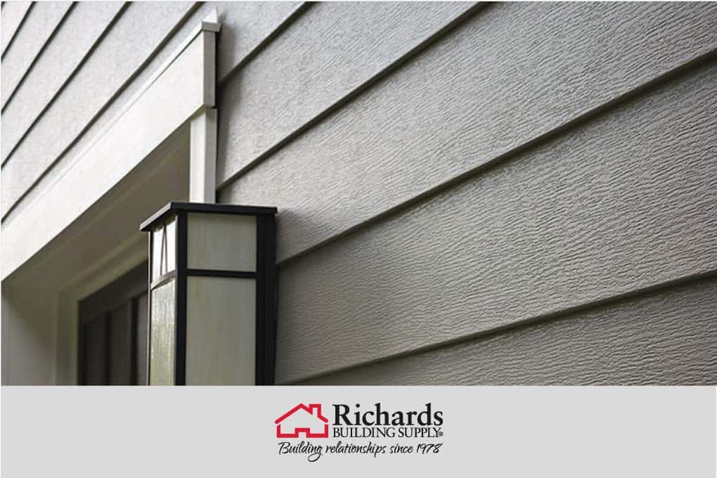 Close up of green siding material on a home next to a door with a light fixture.